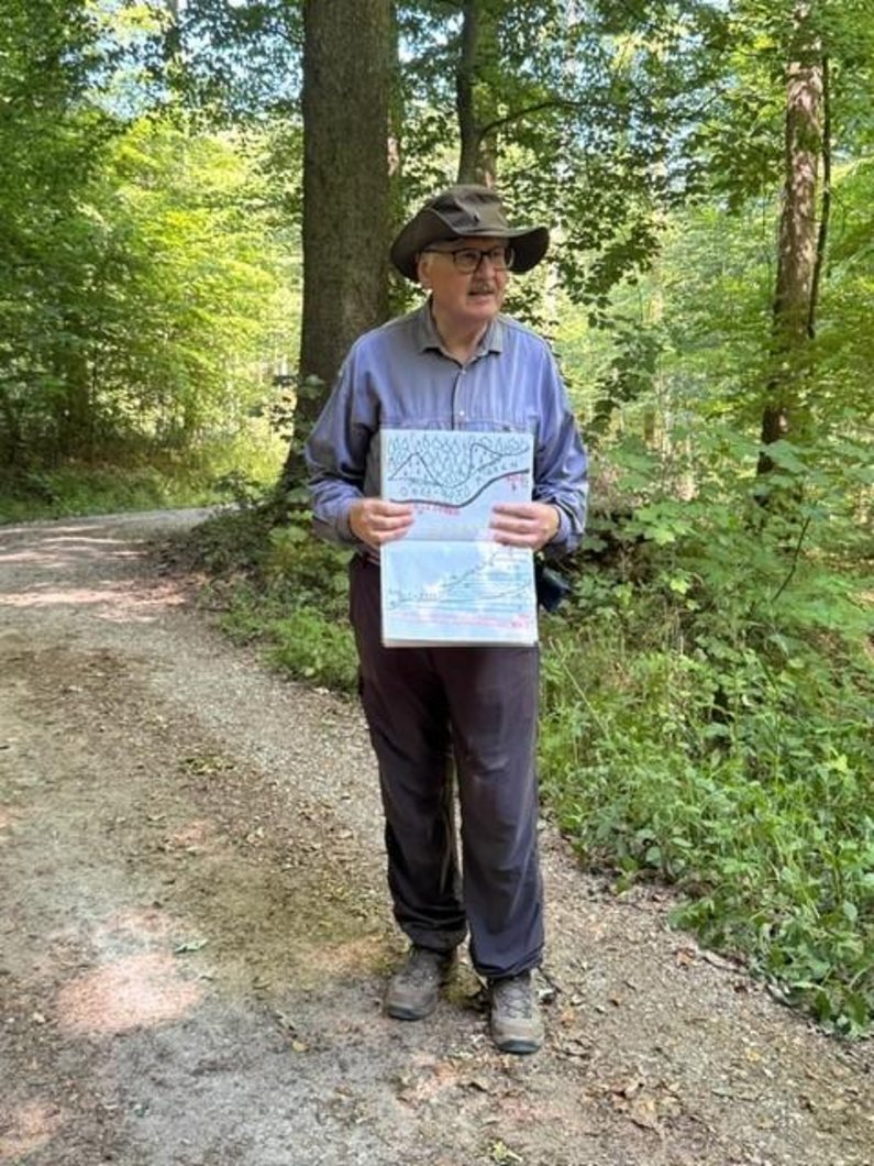 Ein Mann mit Hut und einer Karte steht im Wald