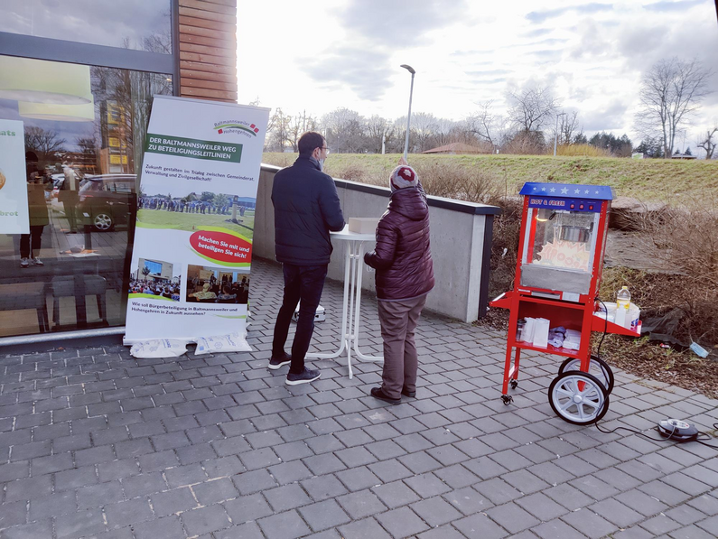 BM Simon Schmid mit einer Bürgerin vor dem Roll up Banner bei der Bürgerbefragung vom 18.02.2022 beim Edeka-Markt in Baltmannsweiler